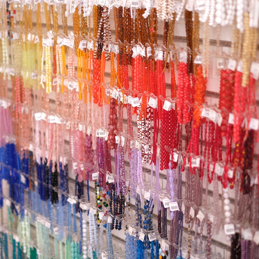 Mur de fils de perles de Bohème classés par couleur, boutique Perles Corner à Paris