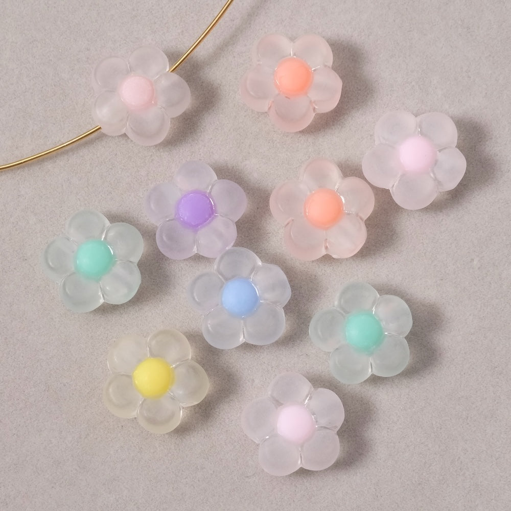 Dix perles en acrylique en forme de fleur aux couleurs pastel variées.