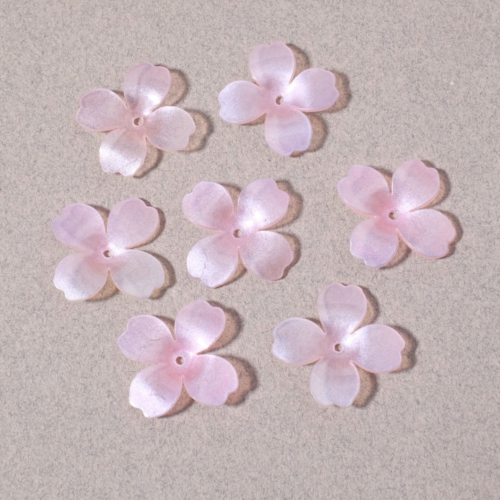 Six pastel pink pearlescent acrylic flower charms with four petals each.
