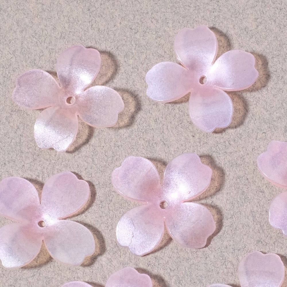 Six pastel pink pearlescent acrylic flower charms with four petals each.