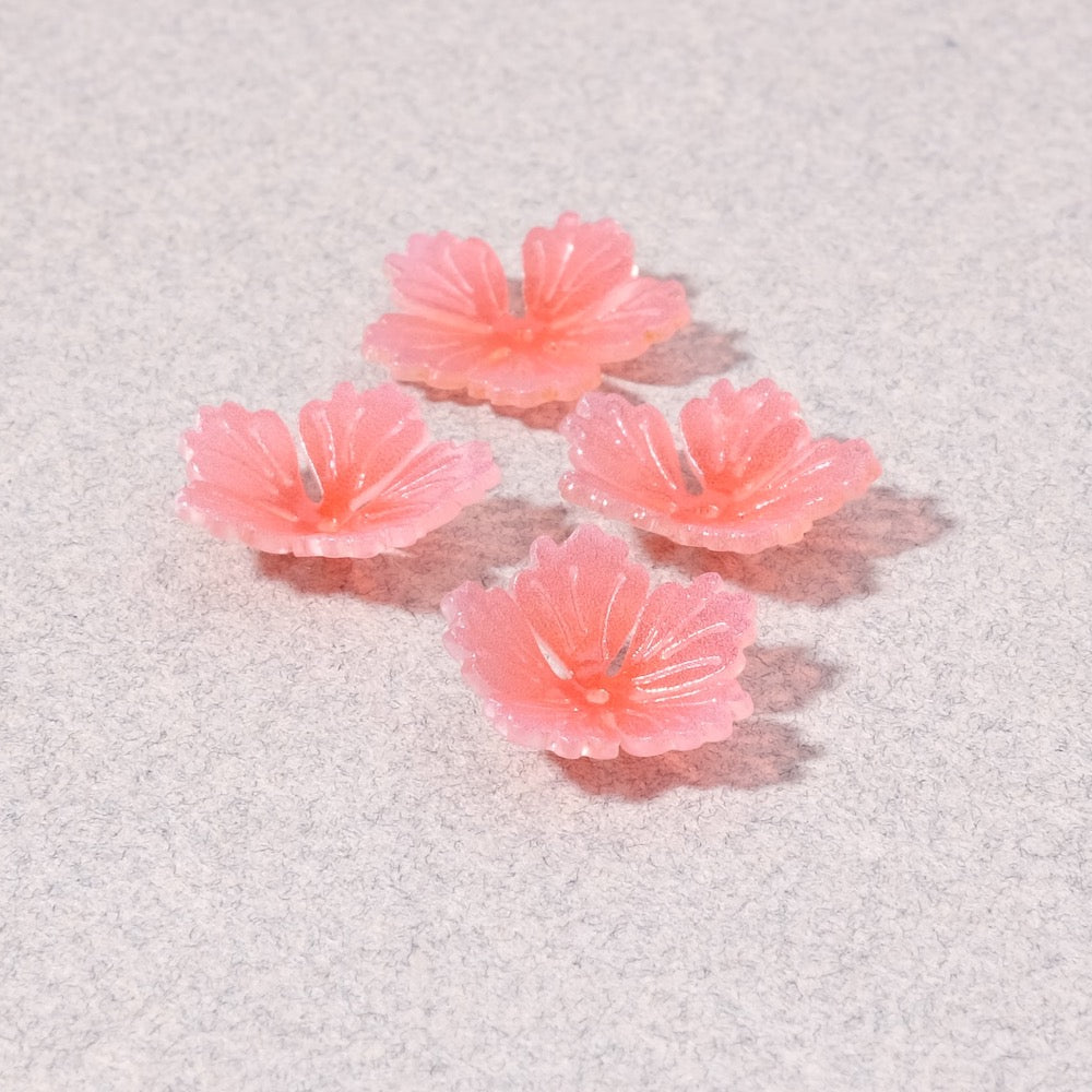 Quatre coupelles fleur en acrylique rose sur fond gris.