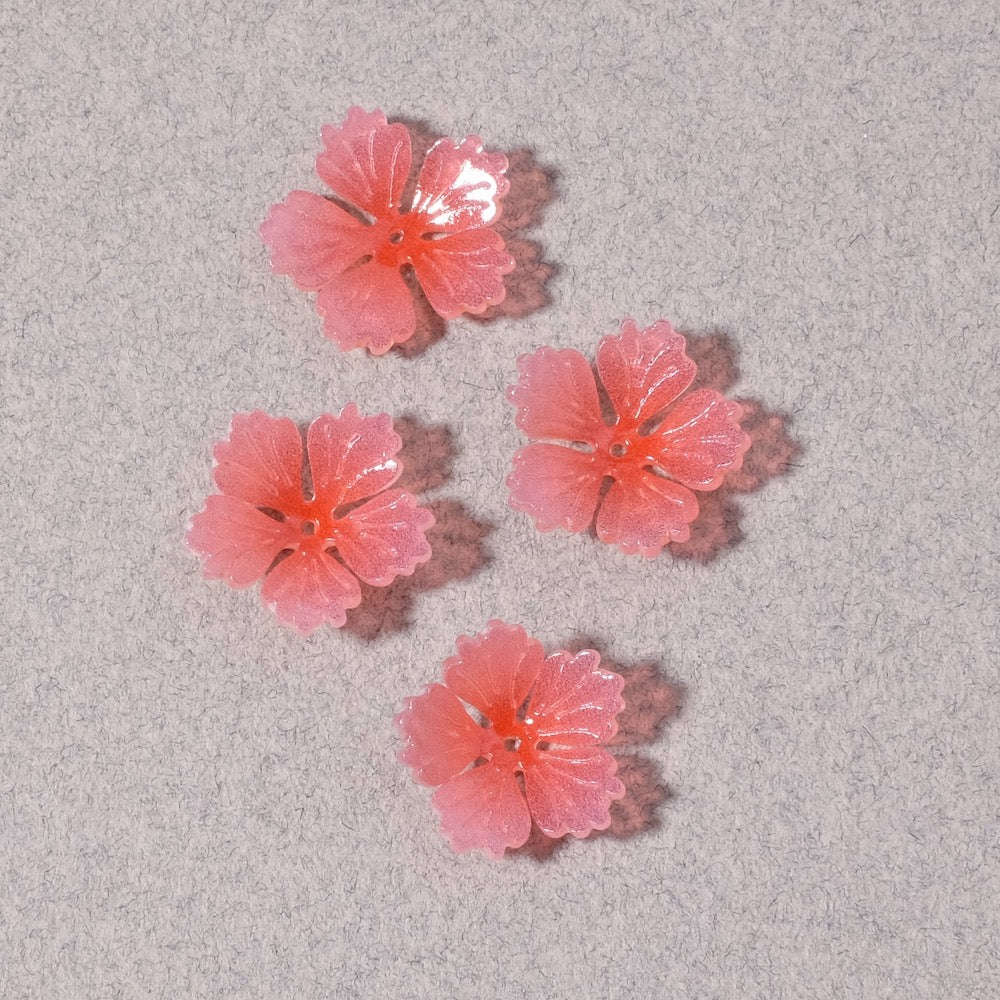Quatre coupelles fleur en acrylique rose sur fond gris.