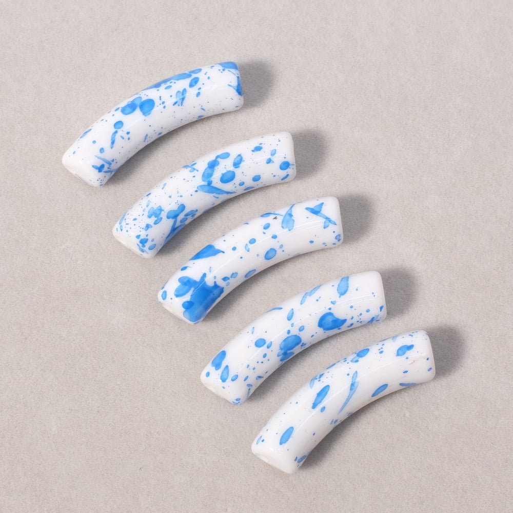 Perles tubes incurvées blanches mouchetées de bleu.