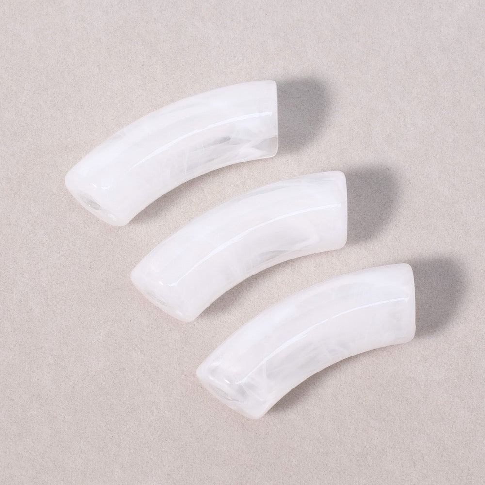 Trois perles tubulaires incurvées en acrylique blanc marbré.