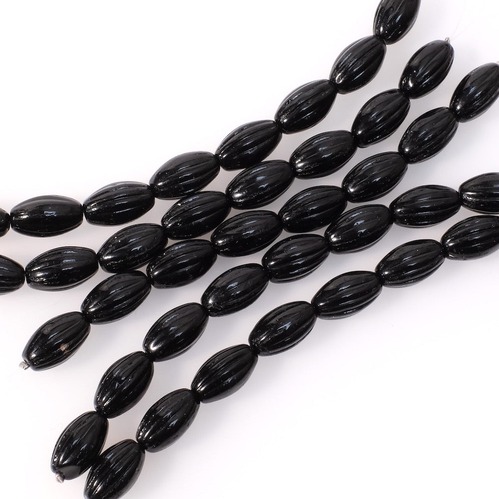 Fil de perles noires en verre strié de forme olive.