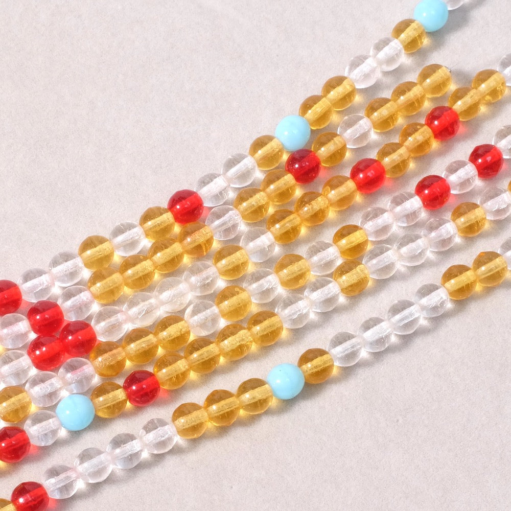 Fil de perles rondes 6mm en verre transparent, jaune, rouge et bleu clair.