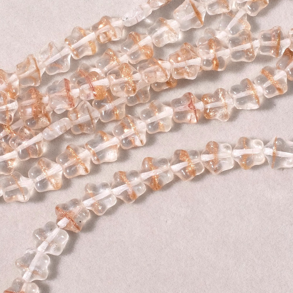 Fil de perles en verre transparent rose en forme de fleur avec paillettes cuivrées.