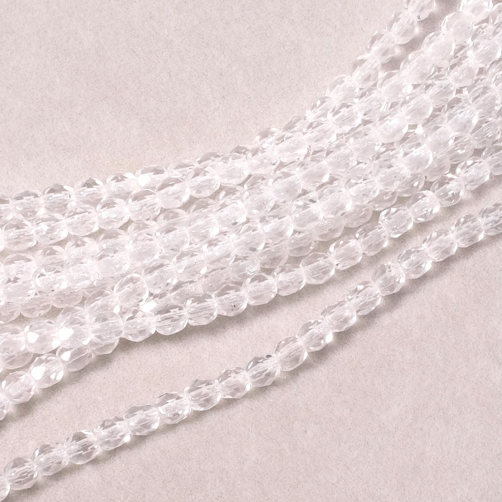 Fil de perles rondes facettées transparentes de 4 mm.
