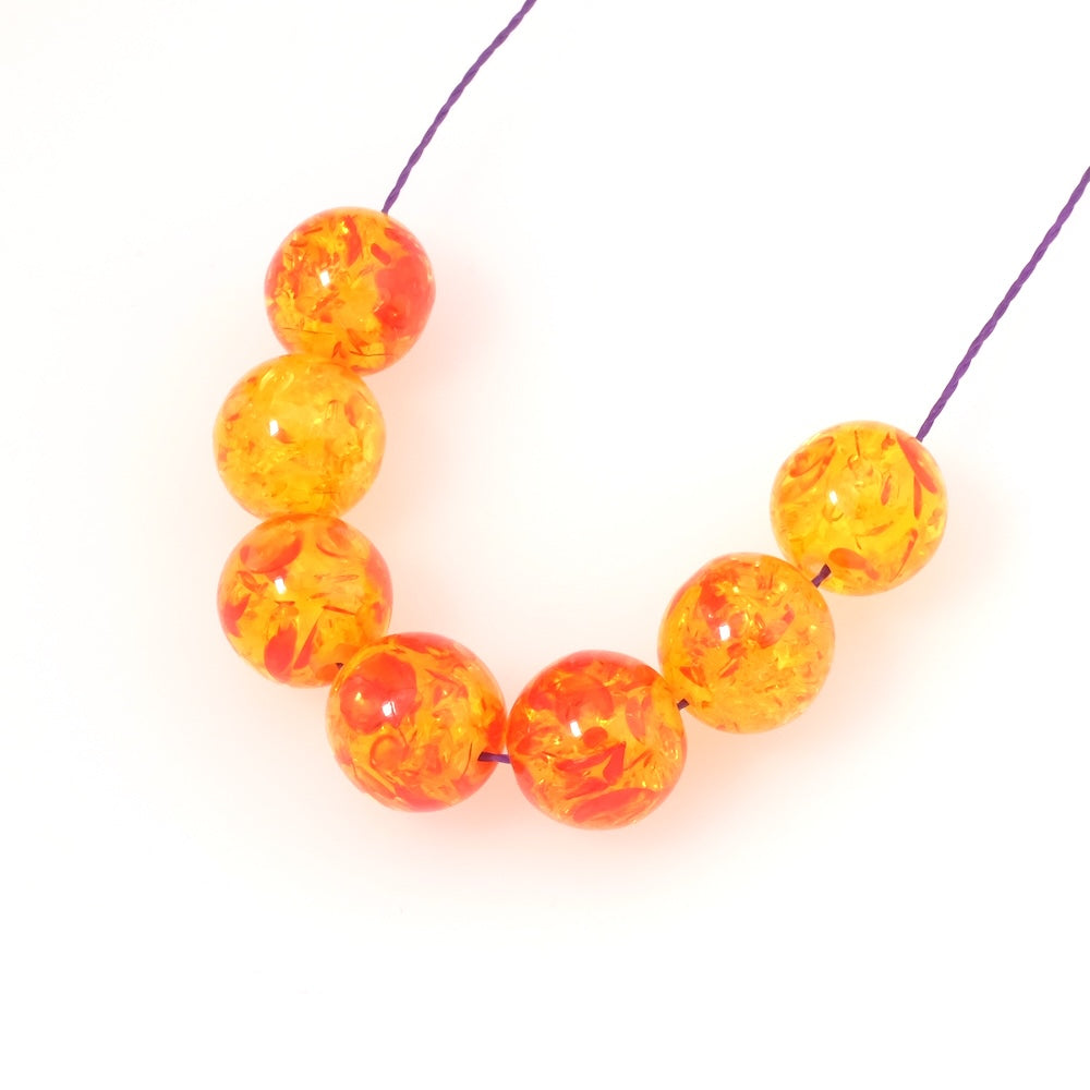Perles rondes en acrylique transparent rouge et jaune avec inclusions.