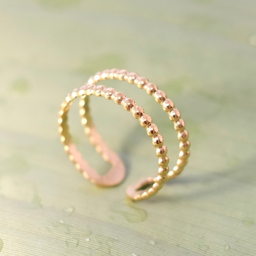 Bague double motif boule dorée en acier inoxydable.