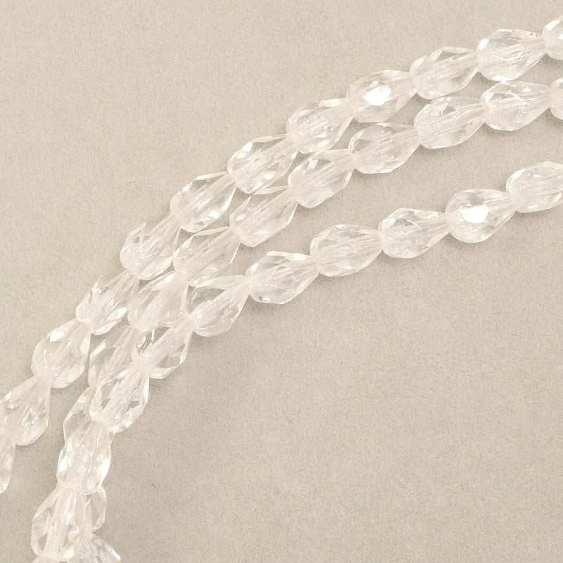 Fil de perles transparentes en verre facetté en forme de goutte.