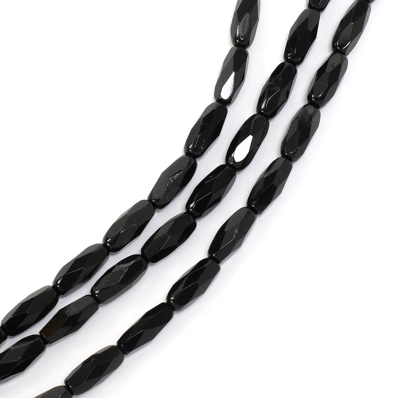 Fil de perles noires allongées à facettes.