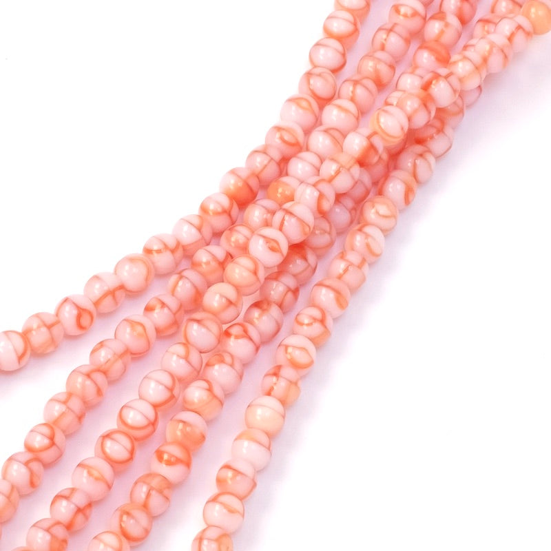 Fil de perles rondes 4mm rose orangé avec des marbrures.