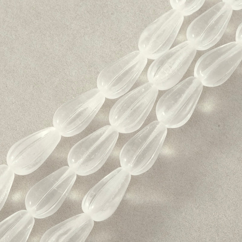 Fil de perles blanches transparentes en forme de goutte allongée avec des stries.