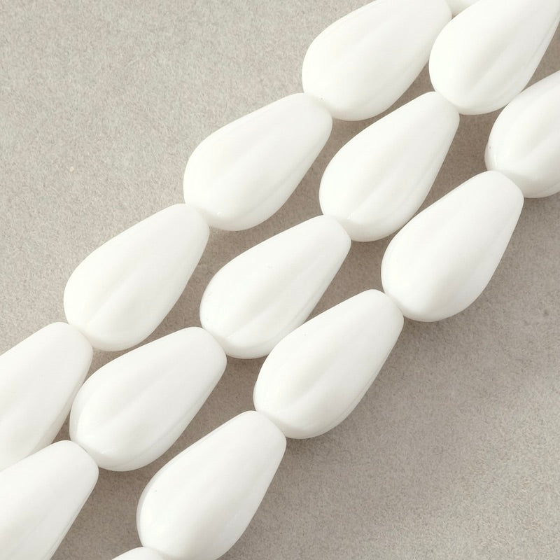 Fil de perles blanches en verre striées en forme de goutte.