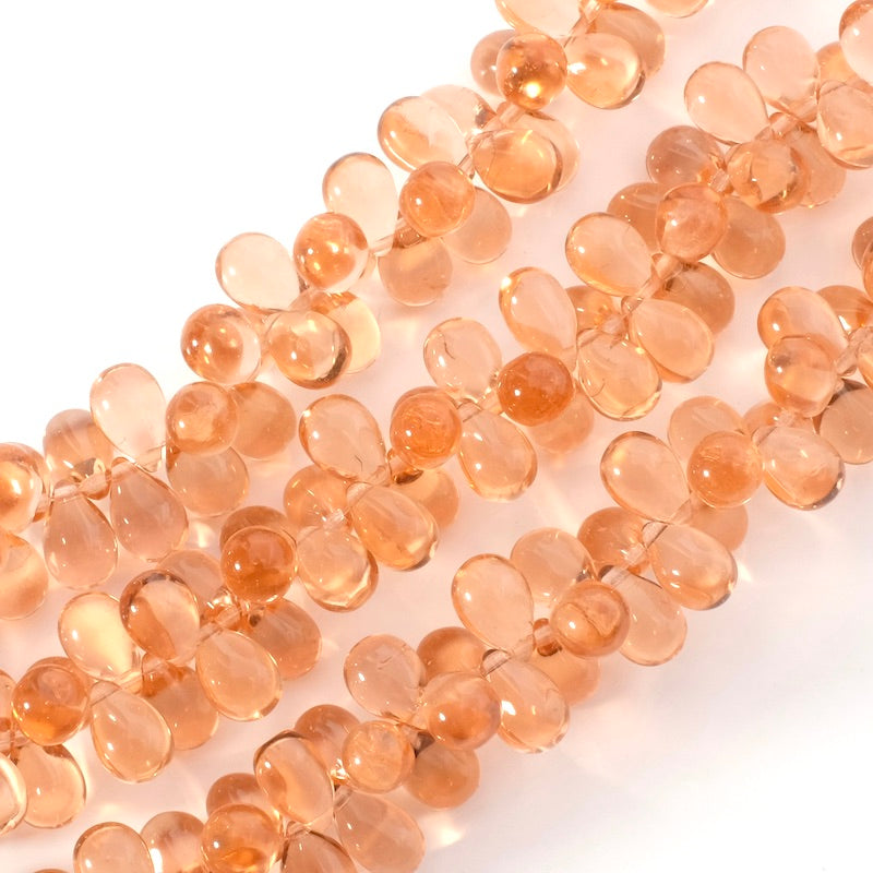 Fil de perles de verre transparent pêche en forme de goutte.