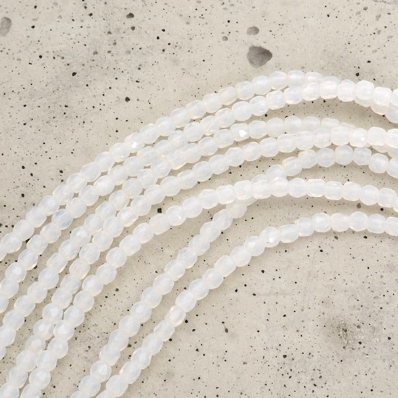 Fil de perles rondes facettées blanc opaline de 2mm.