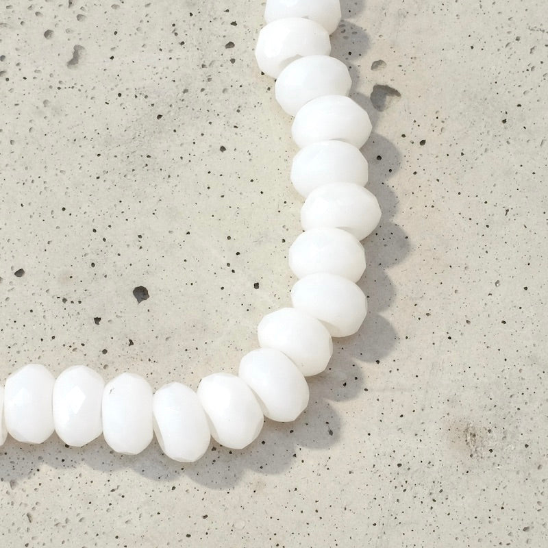 Fil de 22 perles blanches en verre facetté de 9x5mm.