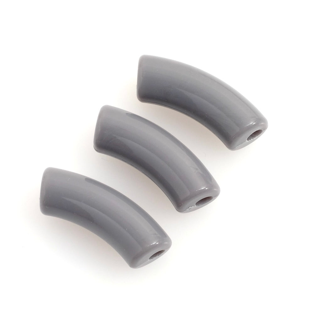Trois perles tubulaires courbes en acrylique gris sur fond blanc.