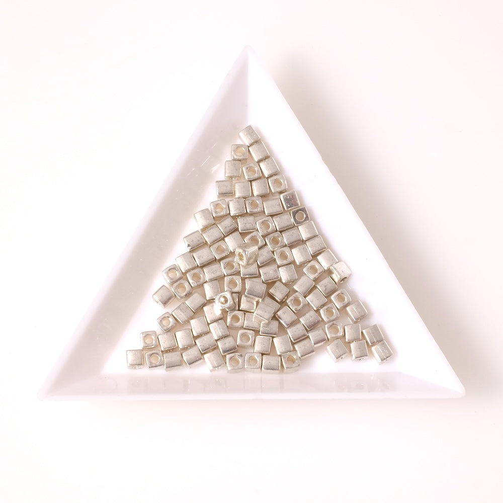 Perles Miyuki Cubes 3mm argentées galvanisées dans un plateau blanc.