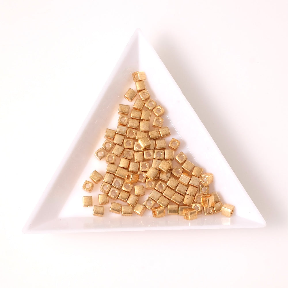 Perles Miyuki Cubes 3mm dorées, en forme de petits carrés.