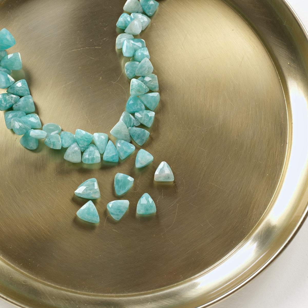 Perles triangles en amazonite vert turquoise sur un plateau doré