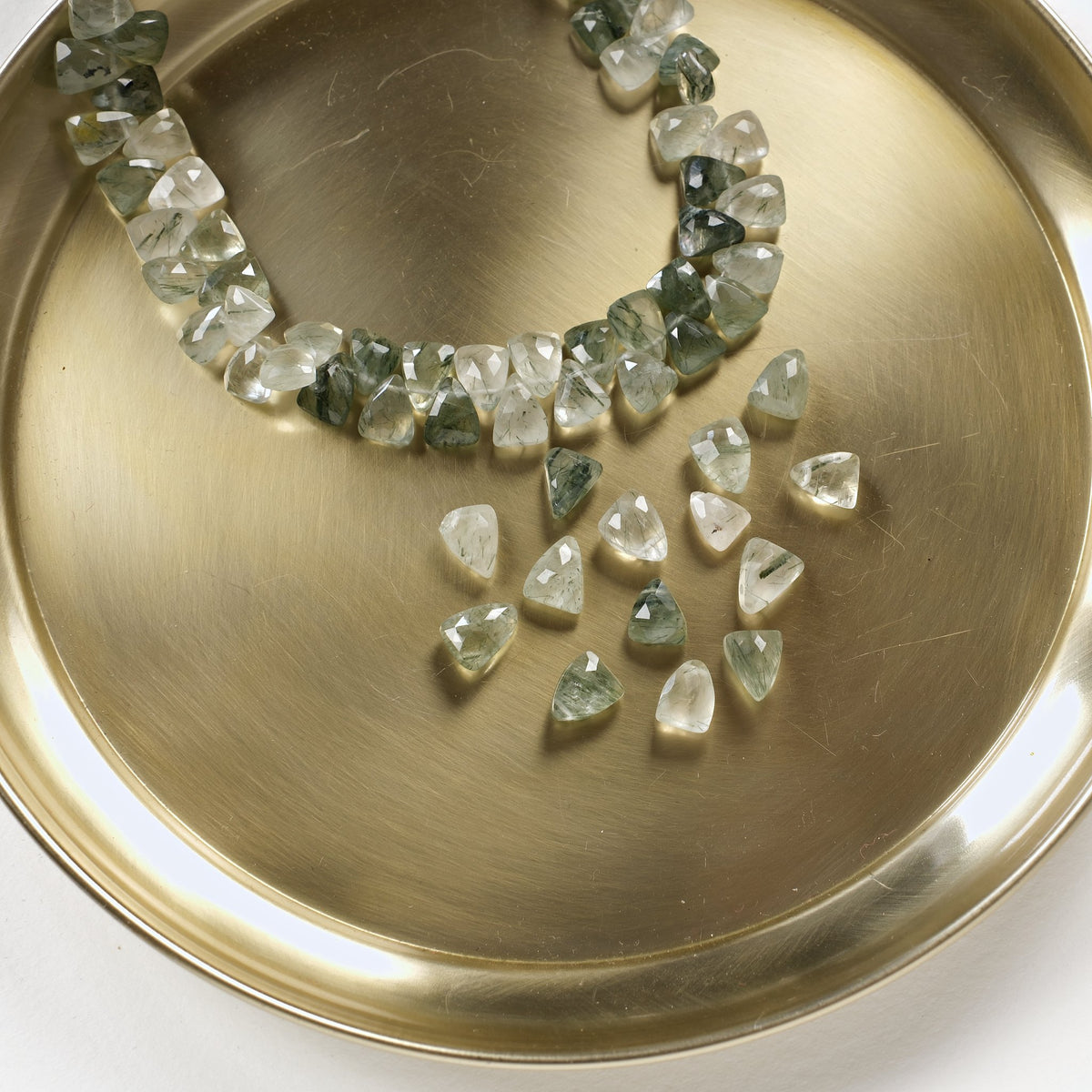 Perles triangles en préhnite verte sur un plateau doré