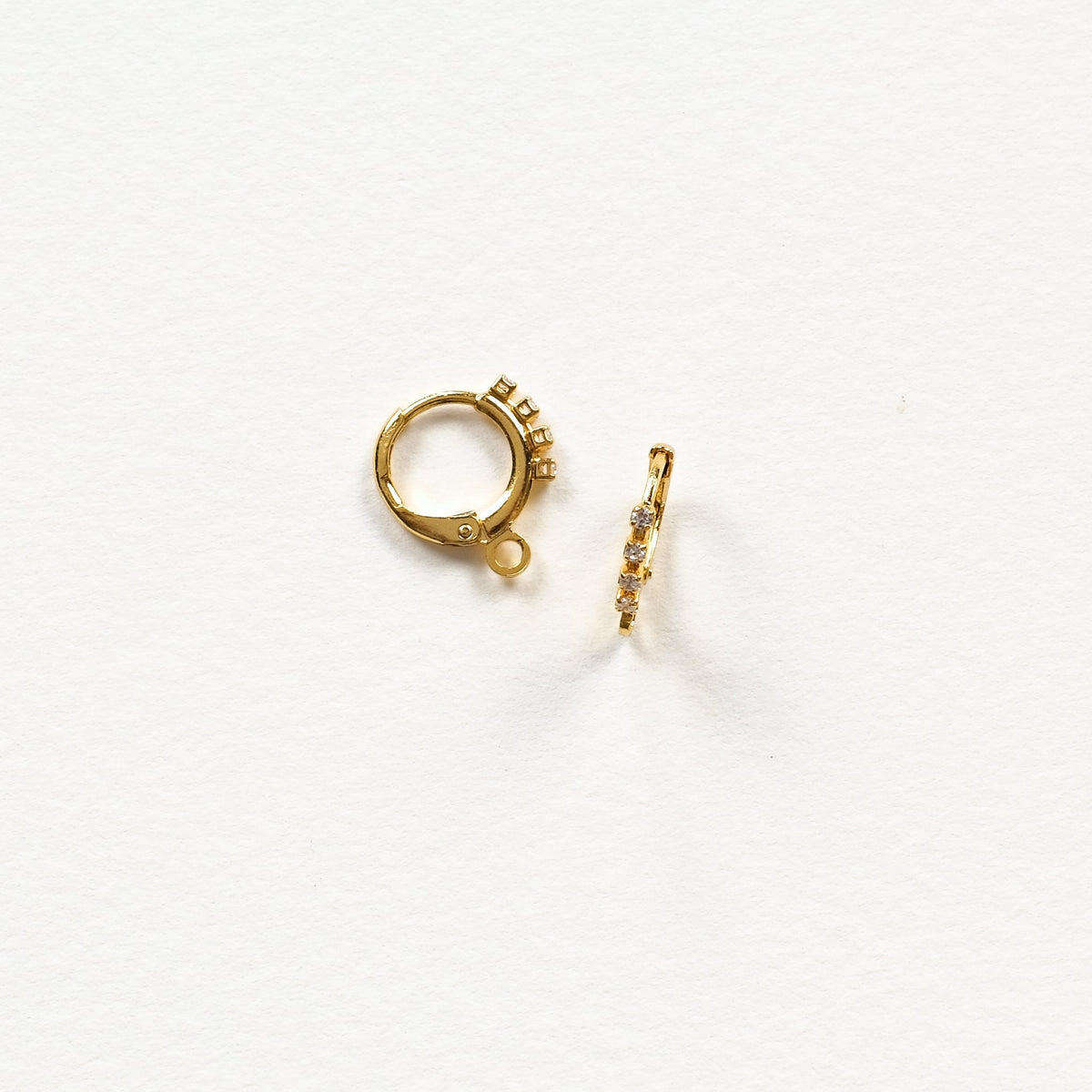 Détail des dormeuses rondes dorées à l'or fin 24K et de leur rang de strass en oxyde de zirconium