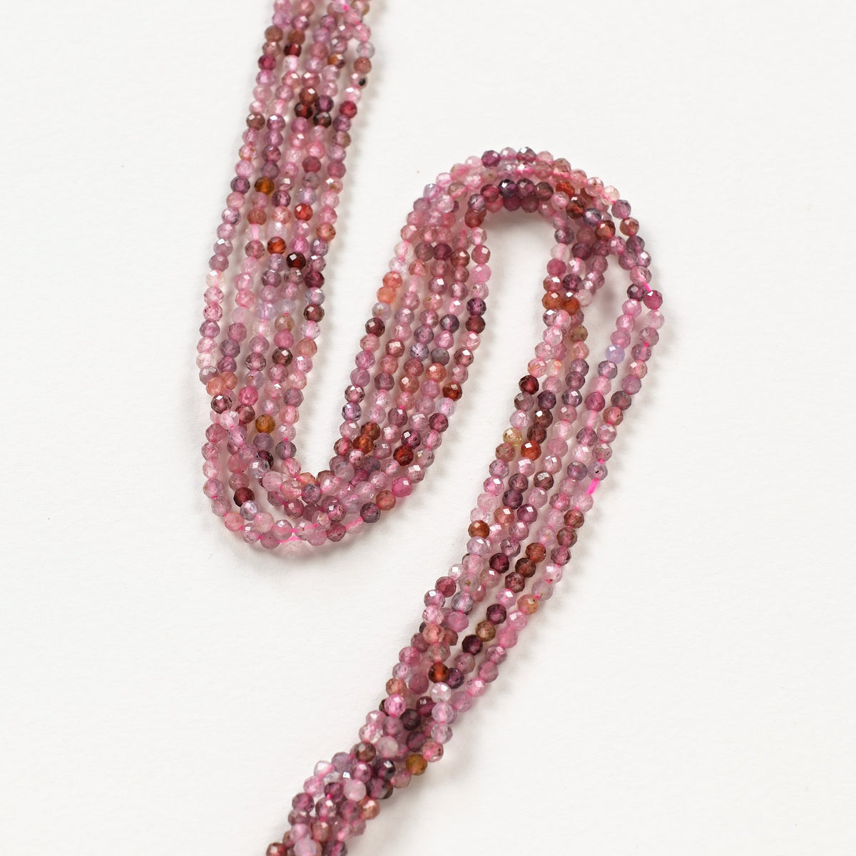 Fils de perles en spinelle multicolore facetté 3 mm, tons framboise, disposés en S