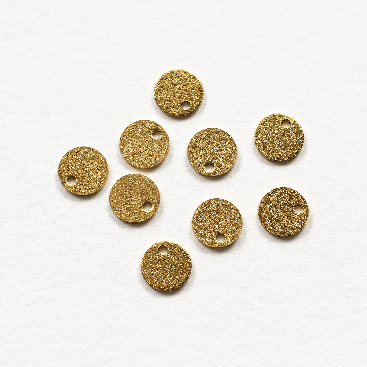 Plusieurs pendentifs ronds dorés effet scintillant avec leur trou de 1,2 mm