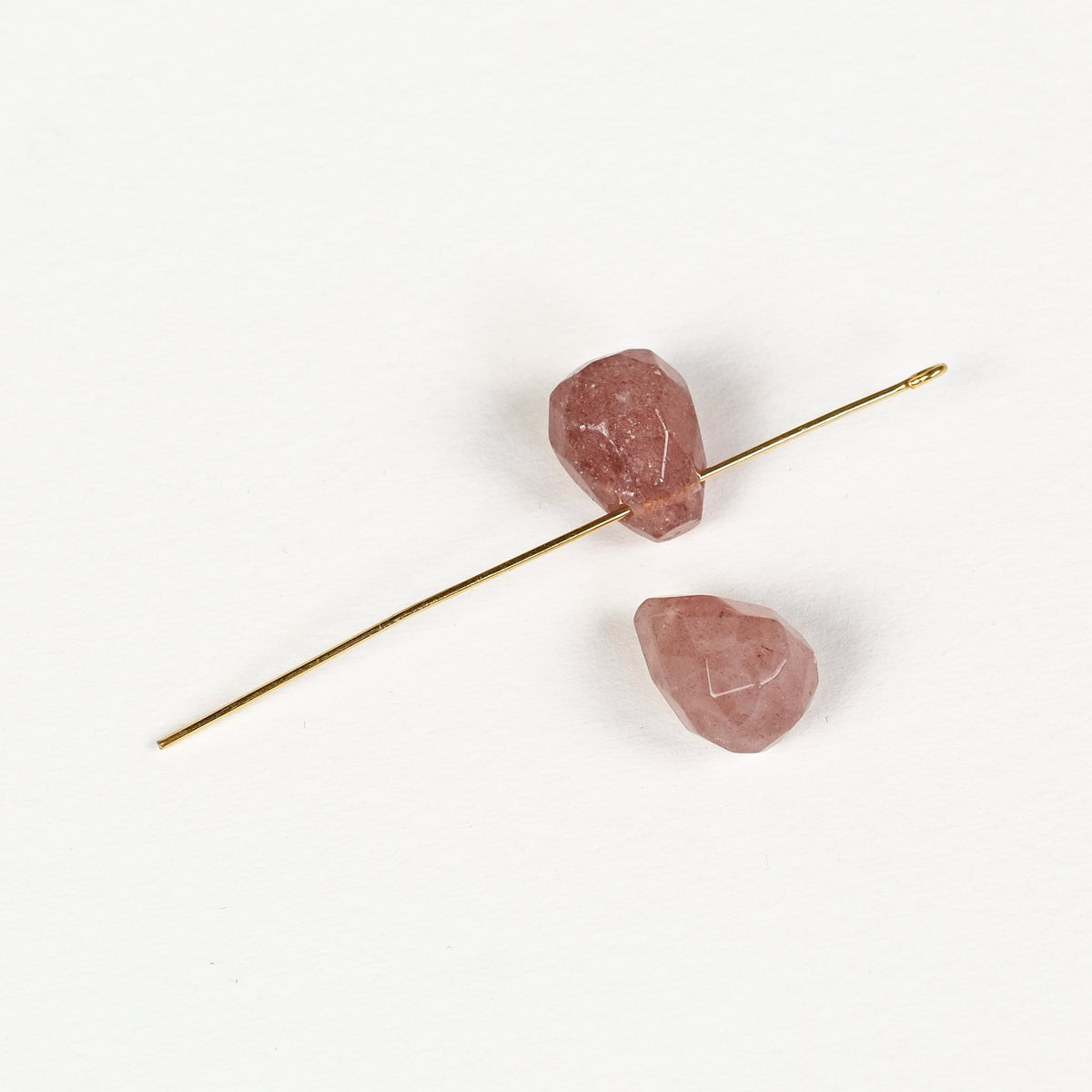Goutte de quartz fraise percée en haut, enfilée sur une tige dorée