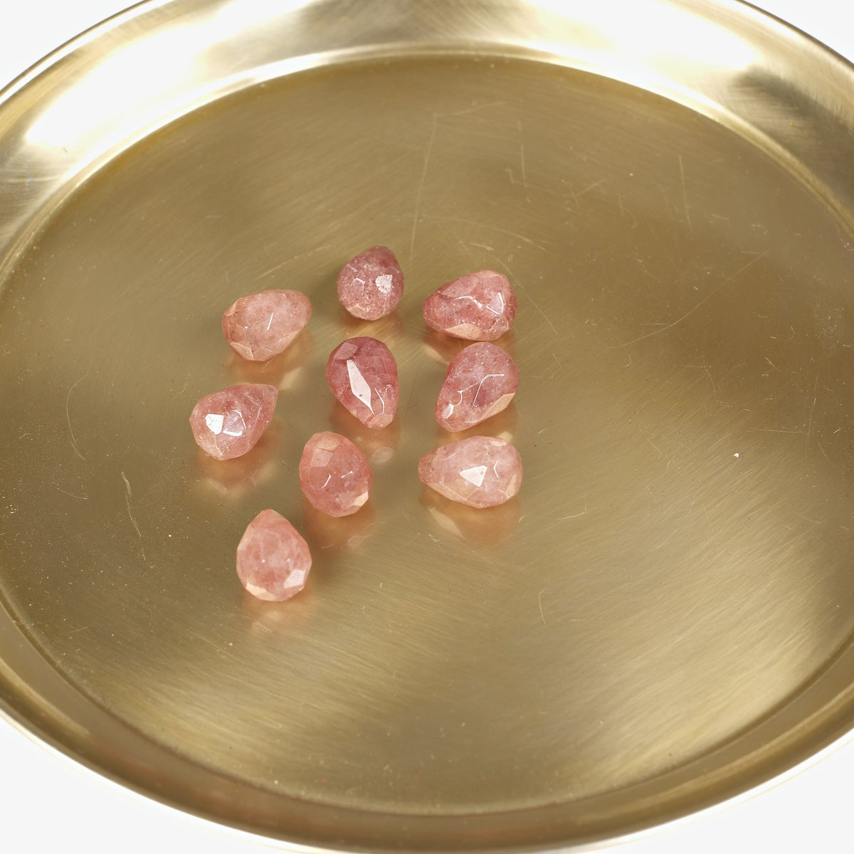 Gouttes de quartz fraise facettées sur un plateau doré