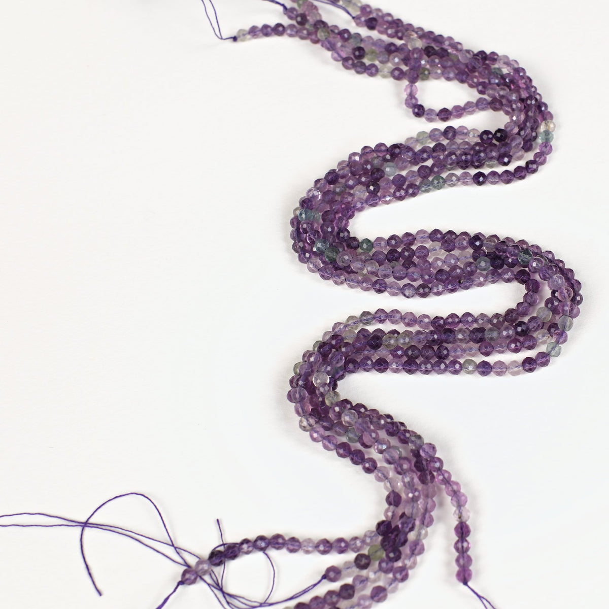 Fils de perles en fluorite violette facettée 3,8 mm disposés en S