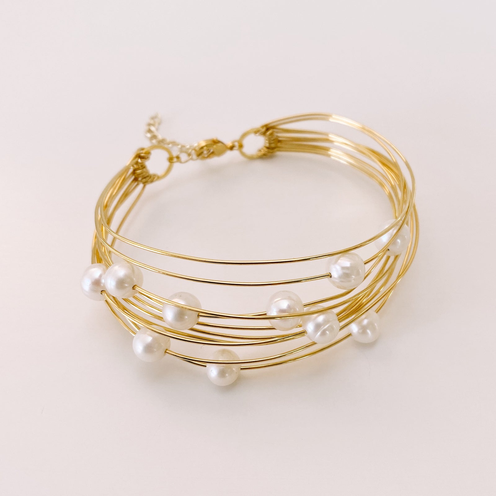 Fil de laiton souple 0,7mm doré à l'or fin 24K enroulé sur fond blanc.