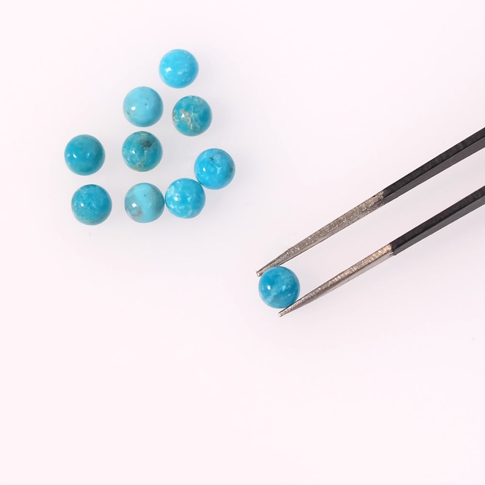 Dix cabochons ronds en turquoise naturelle d'Arizona sont disposés sur un fond blanc, avec une pince tenant un cabochon.