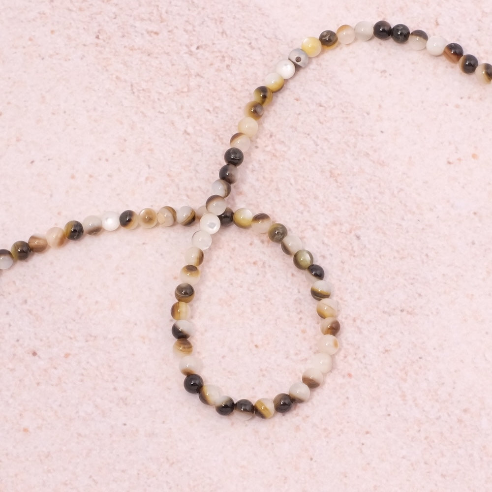 Fil de perles rondes en nacre naturelle blanche et marron.