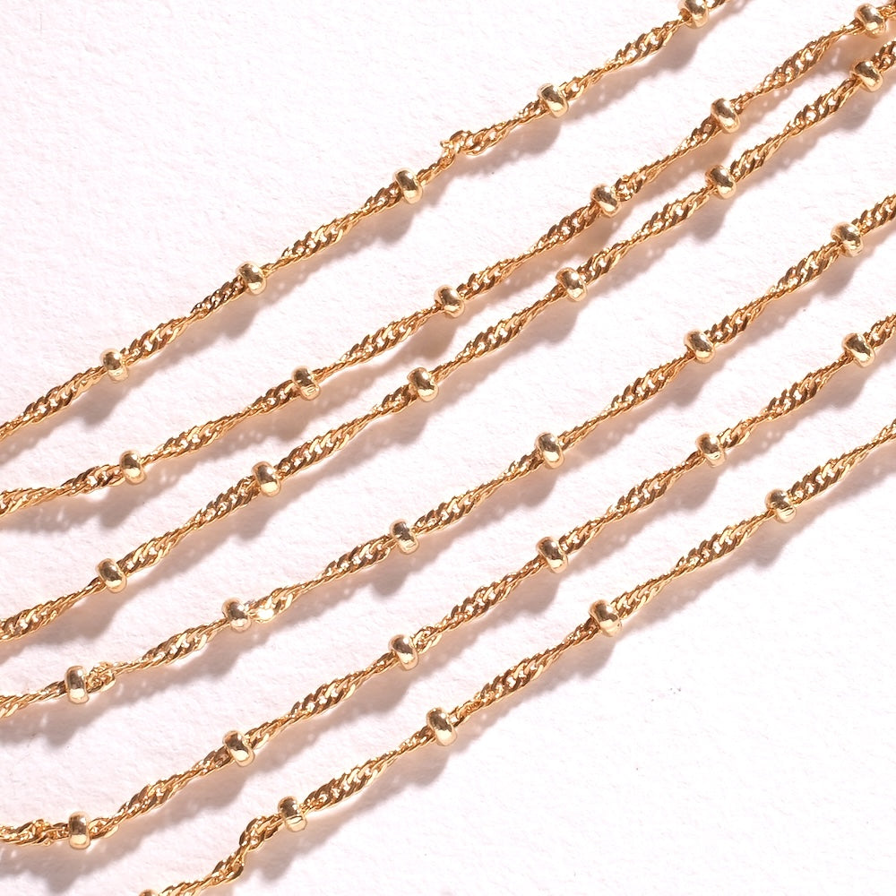 Détail d'une chaîne perlée dorée 24K à maillons torsadés soudés pour bijoux fait main