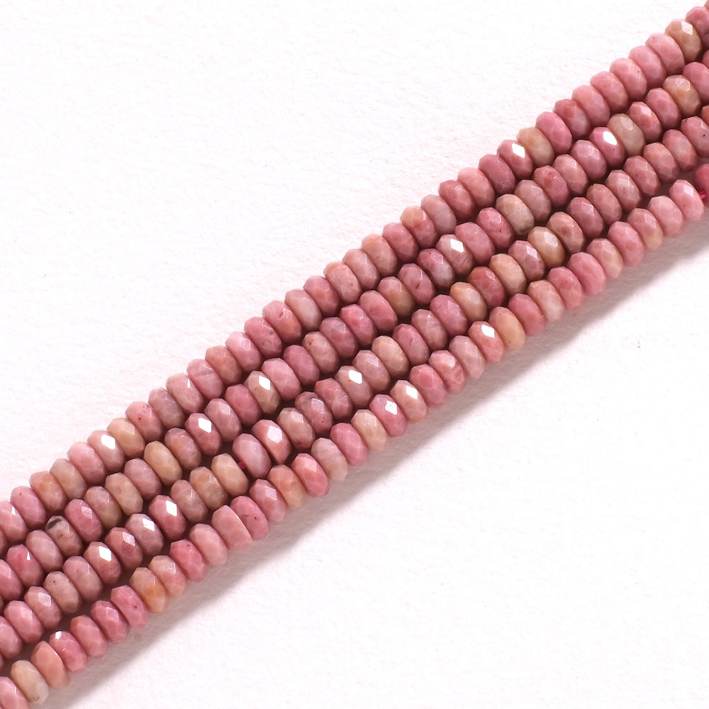 Détail des perles de rhodonite facettées, rose veiné de noir
