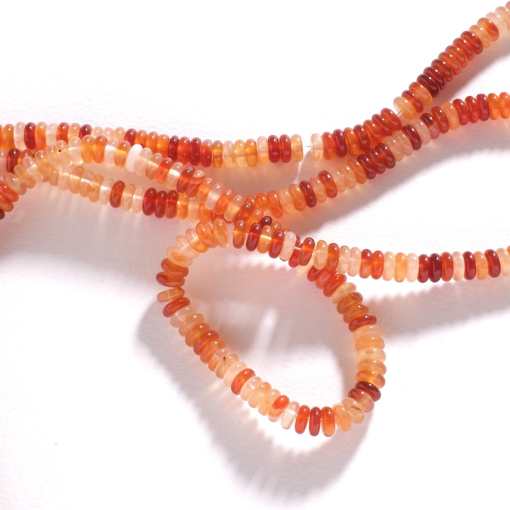 Détail des perles heishi en cornaline, nuances d'orange clair à orange foncé