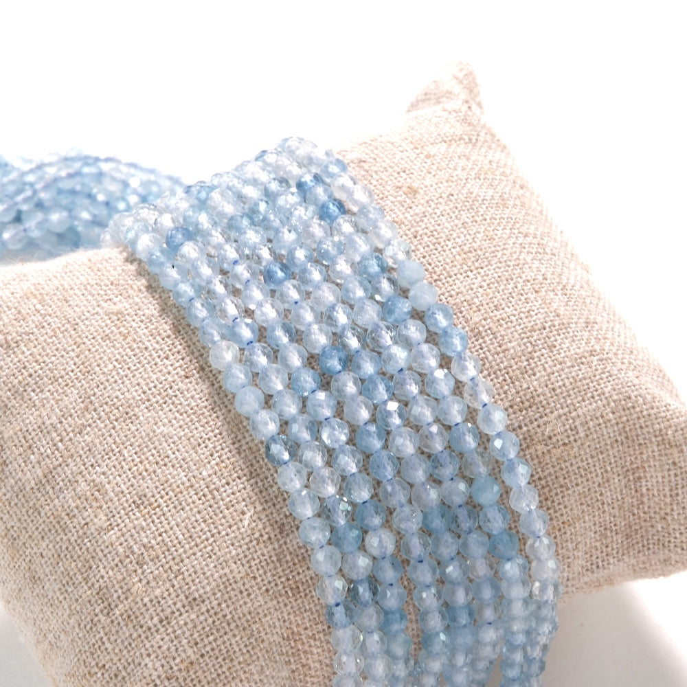 Fils de perles en aigue-marine facettée 3,5 mm sur coussin de lin