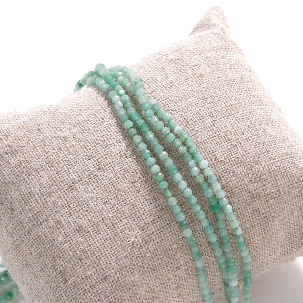 Rangs de perles en émeraude facettée 2 mm sur coussin de lin