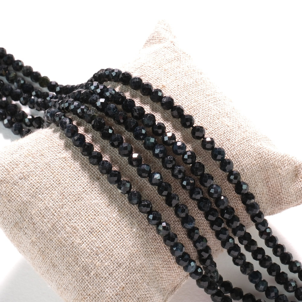 Rangs de perles en tourmaline noire facettée 4 mm sur coussin de lin