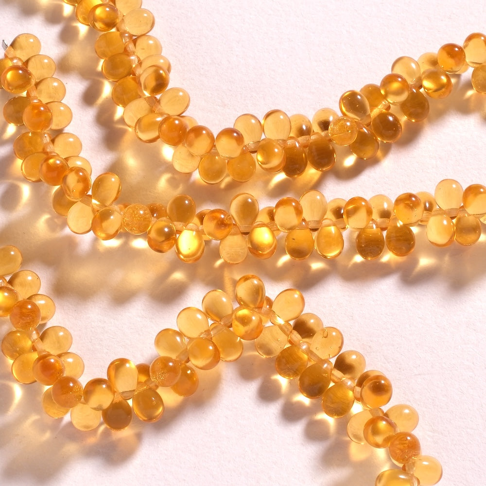Fil de perles de Bohème gouttes 5 x 7 mm en verre orange doré transparent, percées en tête
