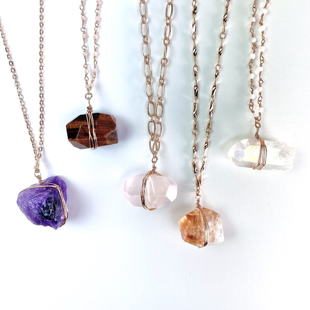 Pointe de Angel Aura Quartz Cristal avec des reflets arc-en-ciel sur fond gris.