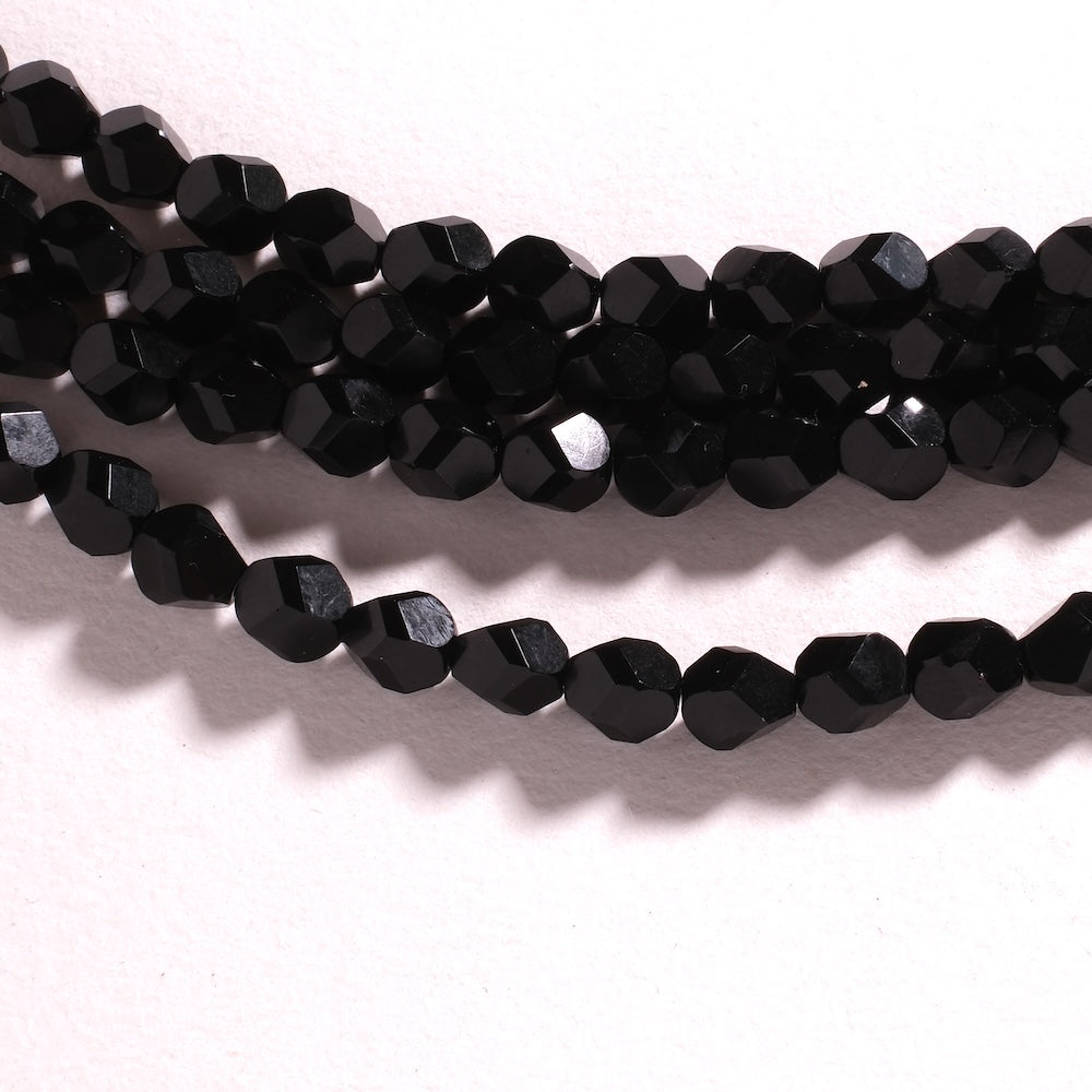 Perles 8 mm noir opaque à larges facettes anguleuses, reflets contrastés sur les plans taillés