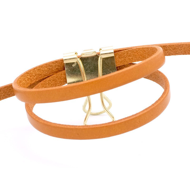 Lanière de cuir plat camel de 5mm de large, tenue par un clip doré.