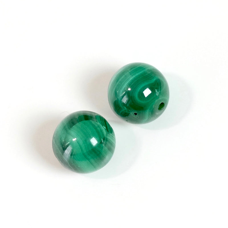 Deux perles rondes naturelles de Malachite verte avec des motifs concentriques.