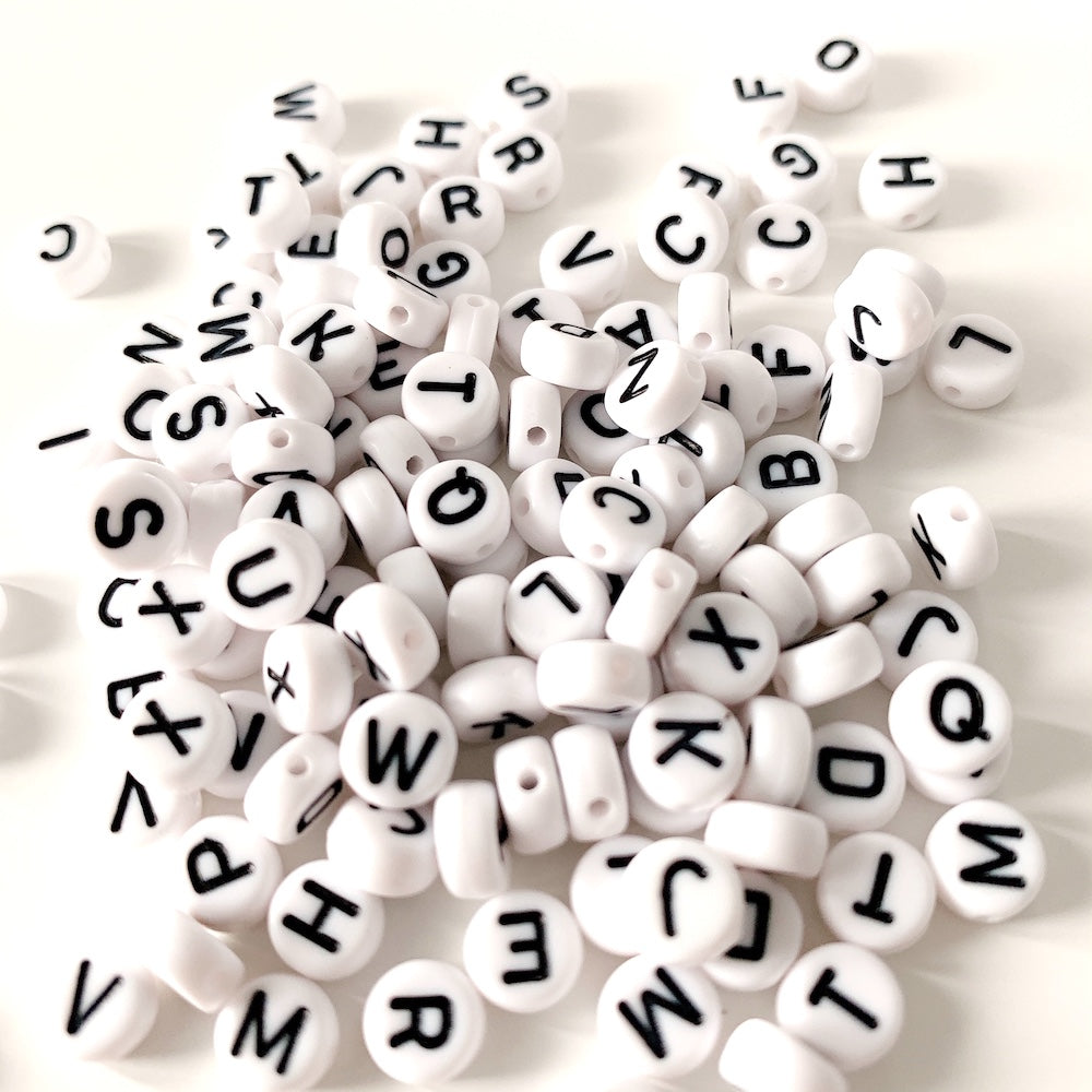 Perles blanches rondes avec des lettres noires imprimées.